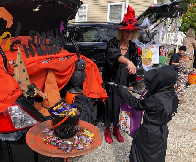 Carol Broughman of Chester drops candy in a trick-or-treater's bag at The Flowered Cheetah Modern & Vintage Boutique during the 2021 Chester Small Business Halloween Trunk or Treat.