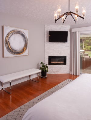 Contemporary and chic: A color-changing gas fireplace insert is set in the corner of this Buechel bedroom.