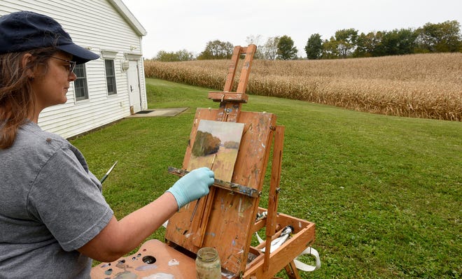 Painter Diana Andrews works on a painting of a field behind the Church of Christ at Alexandria. Andrews is a plein air painter, from the French out of doors, “My goal is to create in an impressionistic style with oil or watercolor paint. I enjoy the challenge of painting fast enough before the light changes.”