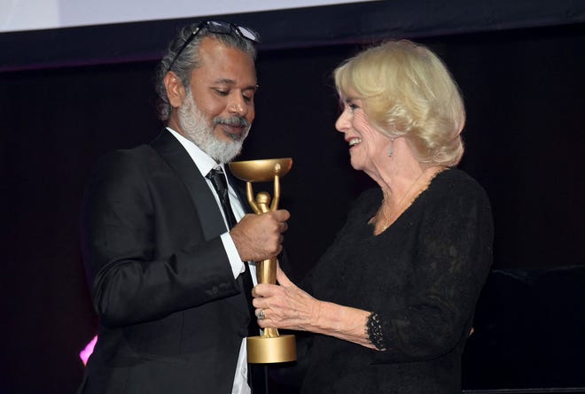 Britain's Camilla, Queen Consort, presents winner Shehan Karunatilaka with the trophee for "The Seven Moons of Maali Almeida" during the Booker Prize at the Roundhouse in London, Monday Oct. 17, 2022. (Toby Melville/Pool Photo via AP)