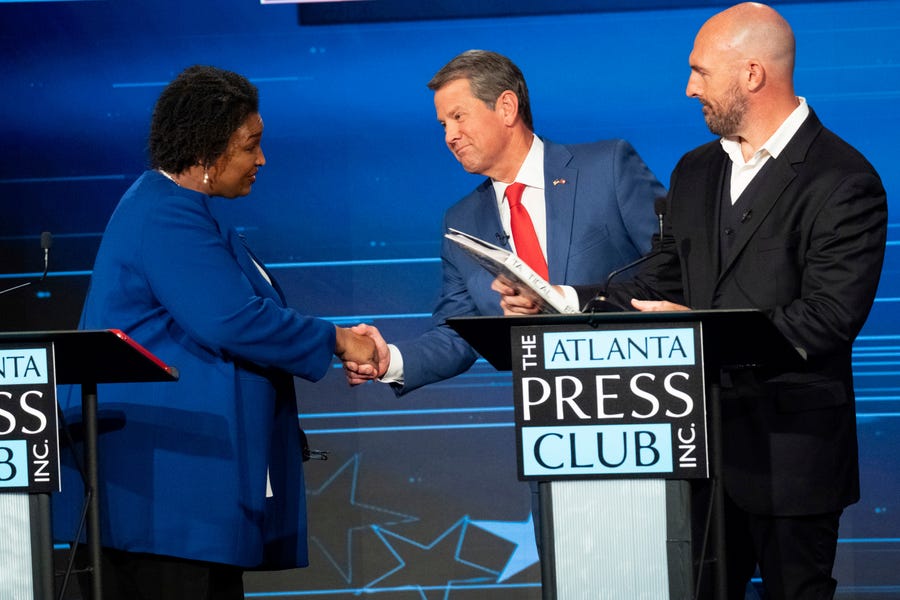 Democratic challenger Stacey Abrams, from left, shakes hands with Georgia Republican Gov. Brian Kemp as Libertarian challenger Shane Hazel stands at right following the Atlanta Press Club Loudermilk-Young Debate Series in Atlanta, Monday, Oct. 17, 2022.