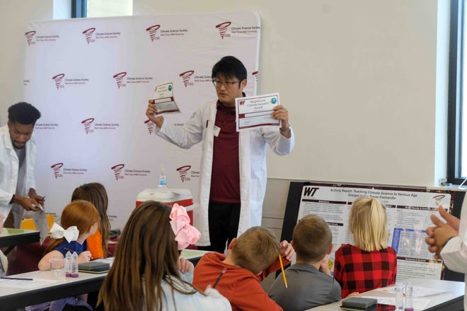 Professor Naruki Hiranuma shows students the certificates they will receive for learning about climate science Tuesday at Spring Canyon Elementary School.