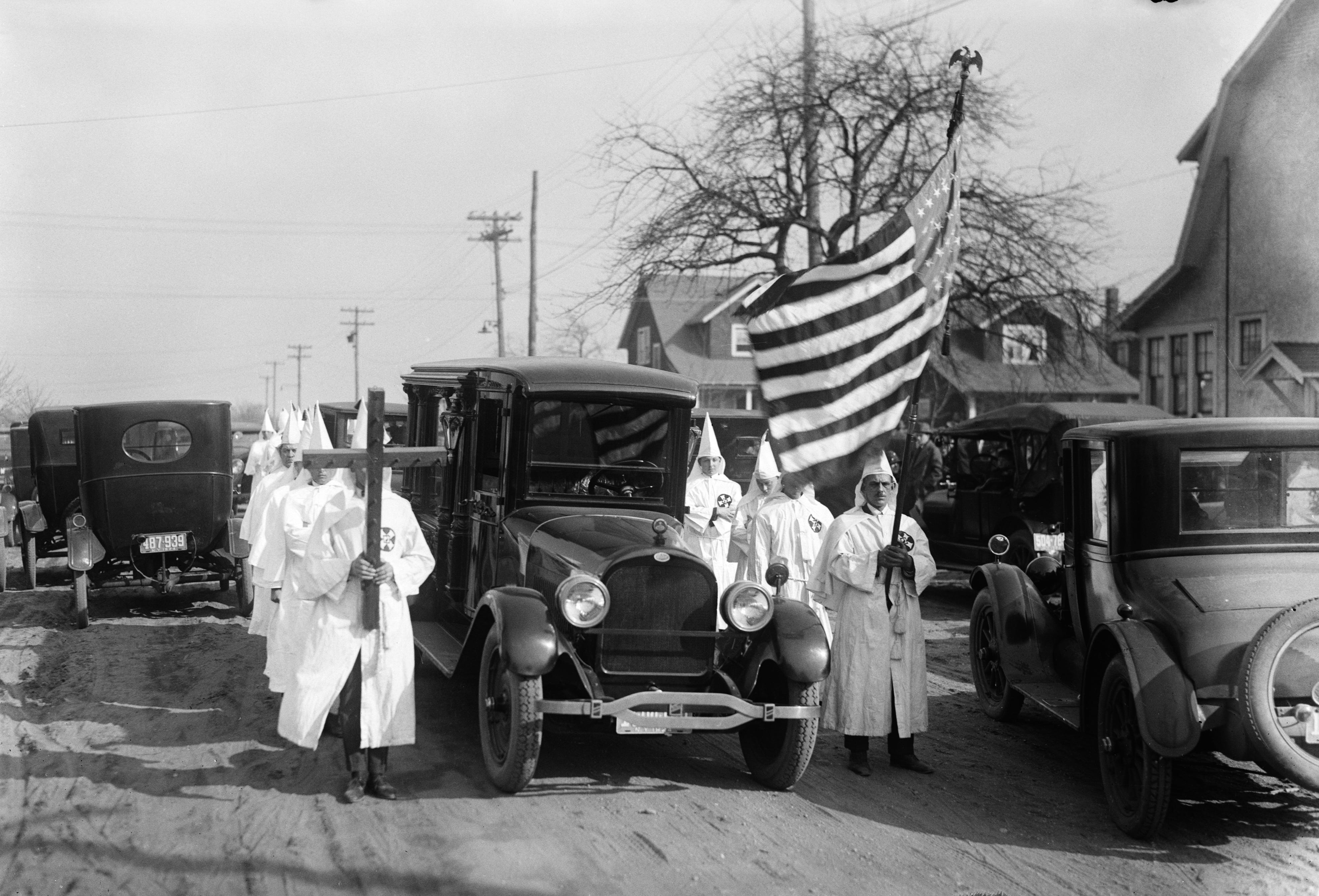Ku Klux Klansmen in Freeport, N.Y., about 16 miles from Syosset, march beside a fellow KKK member's hearse.