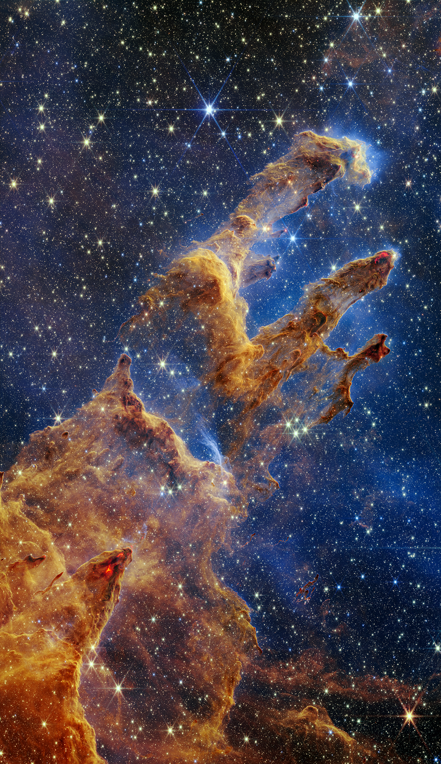 The Pillars of Creation are set off in a kaleidoscope of color in NASA's James Webb Space Telescope's near-infrared-light view. The pillars look like arches and spires rising out of a desert landscape, but are filled with semi-transparent gas and dust, and ever changing. This is a region where young stars are forming – or have barely burst from their dusty cocoons as they continue to form.