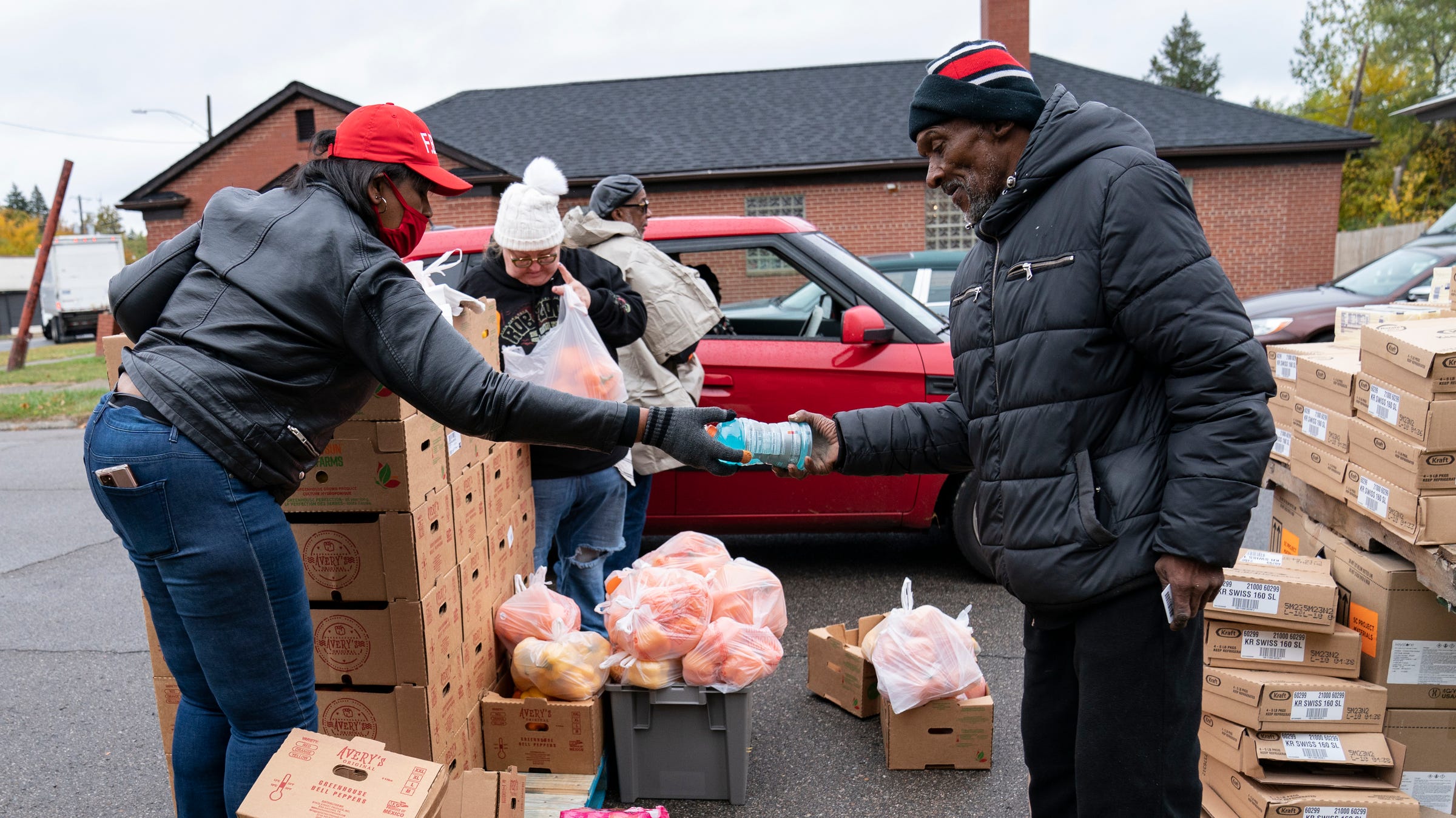 Reverend Dr. Robin de Moore, first woman to lead First Baptist Church on the left, hands over a bottle of Gatorade for boarding Kirk Nichols, 63, of Detroit. Reverend Moore is known as a pioneer when she begins Seniors Day at her church Wednesday, October 19, 2022. Moore, with the help of Forgotten Harvest, distributes food to seniors with the help of volunteers.