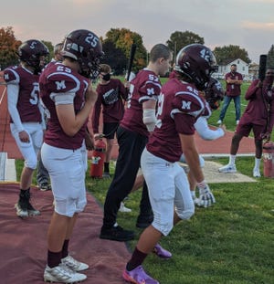 Jacob Bush, (middle without helmet) stands among his Mishawaka football teammates after his accident.