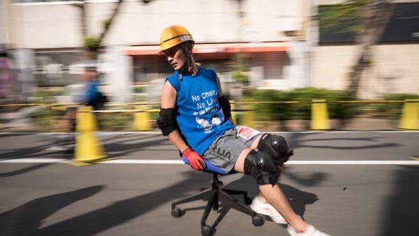 A racer riding on an office chair competes during 