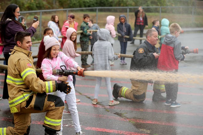 Bremerton probationary firefighter Tony Slauson helps steady a fire hose as third-grader Pheobe Murdock, 9, turns the fire nozzle at Bremerton's Crownhill Elementary School on Monday.  Students at Crownhill participated in Bremerton Fire's Ready For Water program, where got a lesson on fire safety.