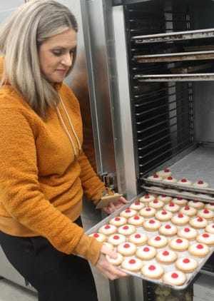 Megan Ackroyd pulls out a tray of Empire Biscuits at the new home of Ackroyd's Scottish Bakery in Redford Township.