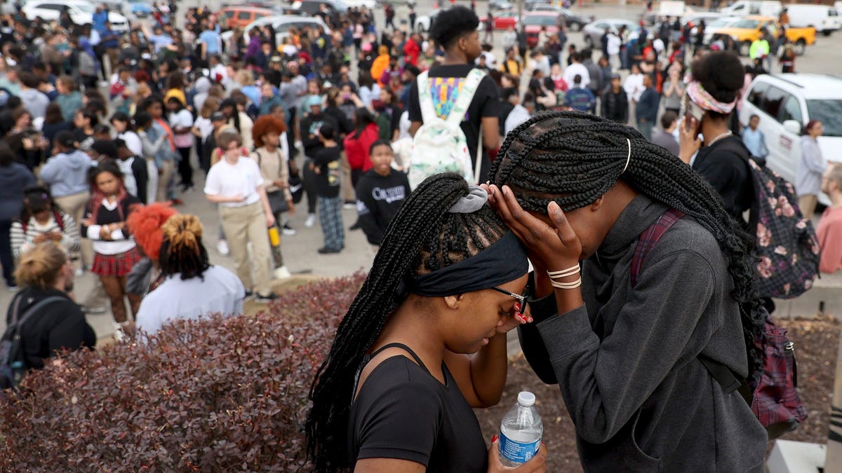 Students stand in a parking lot near the Central Visual & Performing Arts High School after a reported shooting at the school in St. Louis on Monday, Oct. 24, 2022.