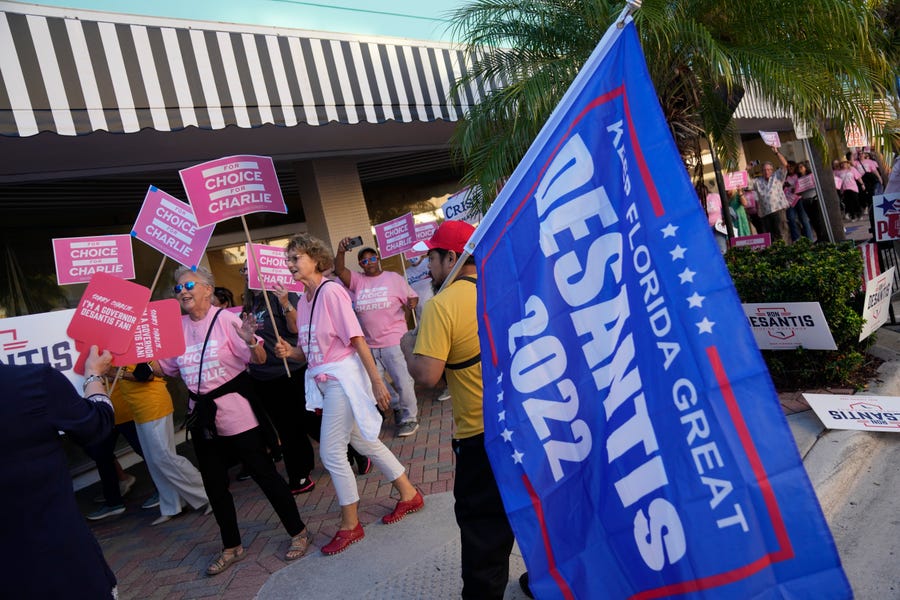 Supporters of Democratic candidate for governor Charlie Crist march past a supporter of Florida's Republican Gov. Ron DeSantis, as they arrive at the Sunrise Theatre ahead of a debate between DeSantis and Crist, in Fort Pierce, Fla., Monday, Oct. 24, 2022.