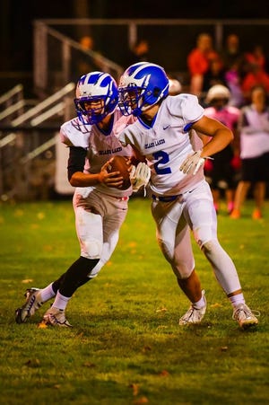 Inland Lakes sophomore quarterback Aidan Fenstermaker (1) decides whether or not to hand off to junior running back Payton Teuthorn (2) during a varsity football matchup at Mesick on Saturday, Oct. 22. The Bulldogs captured a 68-33 victory in their road clash.