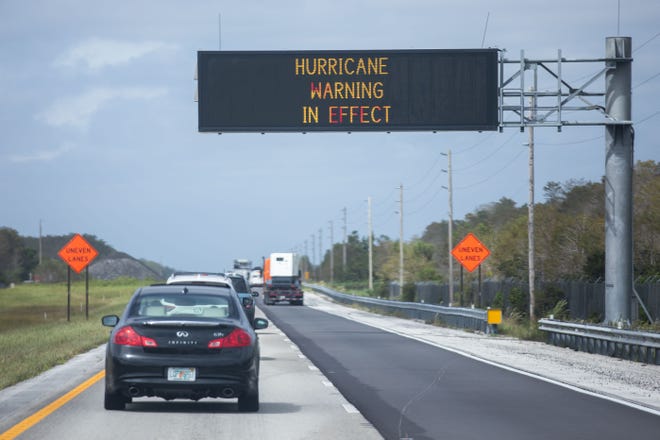 Cars driving northbound on Alligator Alley pass under a traffic sign reading "Hurricane Warning In Effect," after Hurricane Ian passed through Southwest Florida Wednesday afternoon in unincorporated Florida, on Thursday, September 29, 2022.