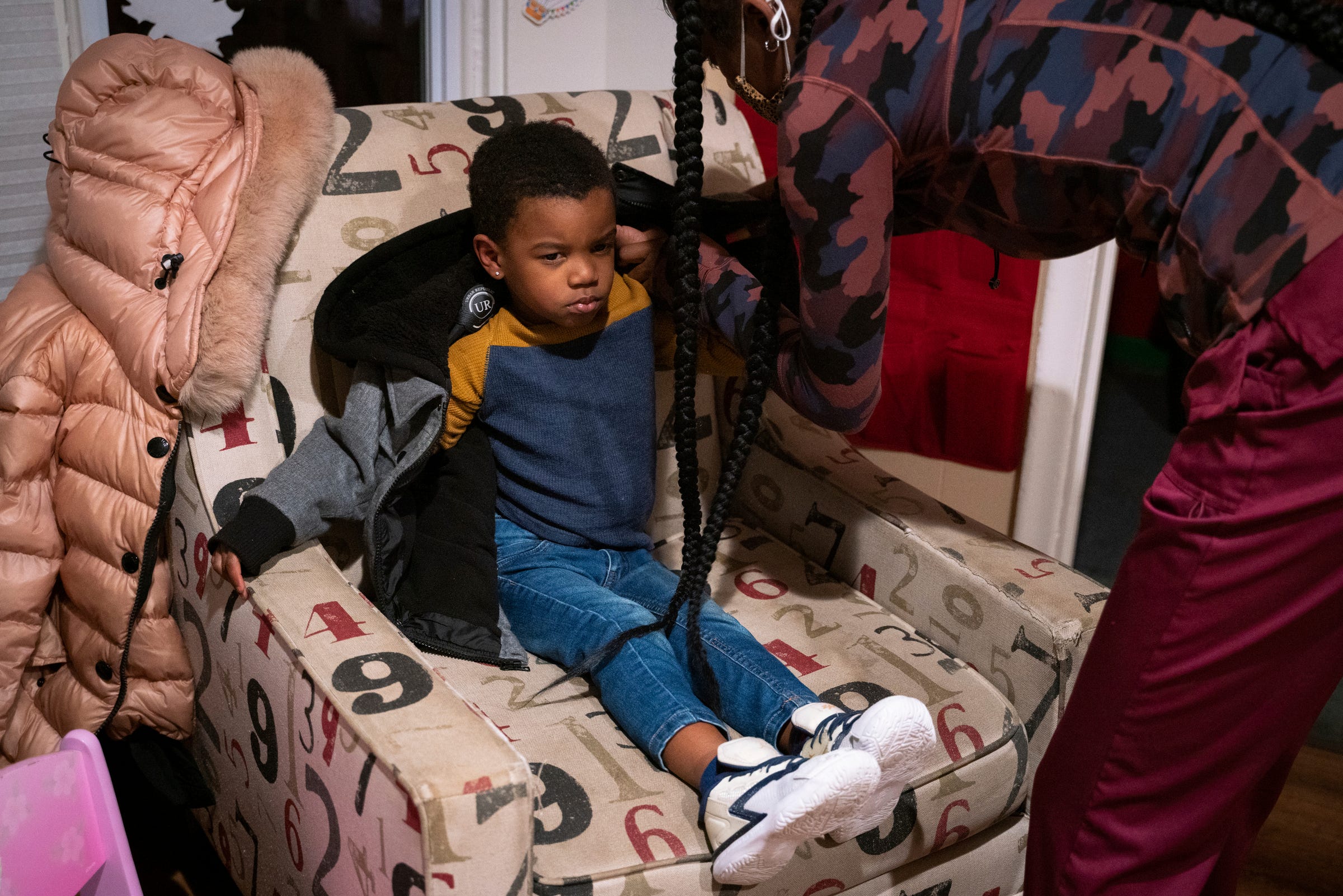 DeAndre Terry, 3, sits up while half asleep, as Arionne Brock, 21, helps put his jacket on during a late night at Angels of Essence Child Care Centre in Detroit on Thursday, Oct. 20, 2022.