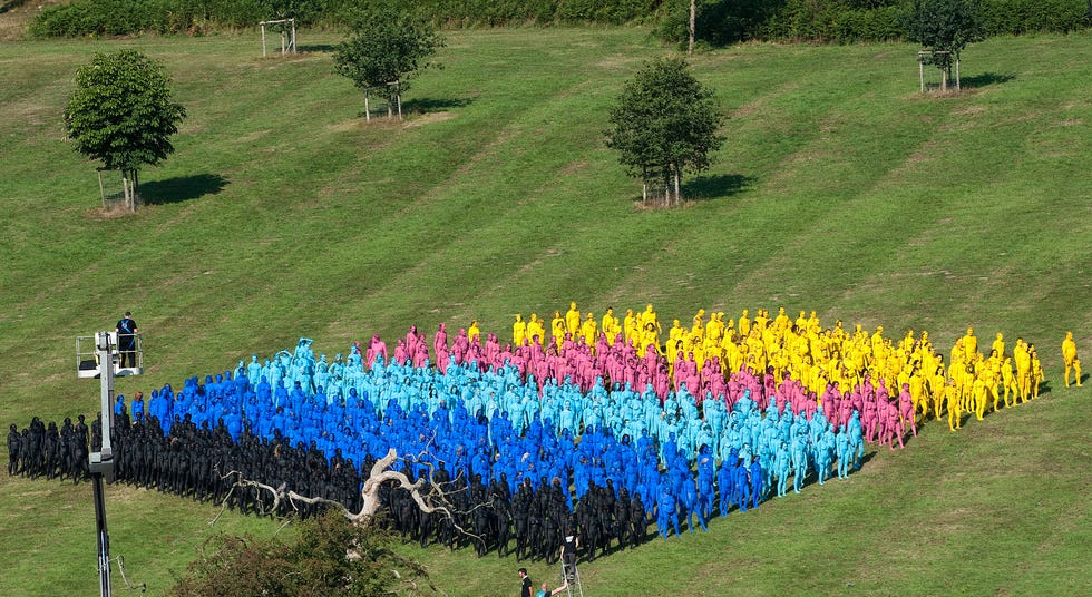 Anëtarët e publikut marrin pjesë në një instalacion të zhveshur për Tunick (majtas në kullë) në festivalin Big Chill pranë Ledbury në Herefordshire më 8 gusht 2010. Të përfshirët u pikturuan me bojëra trupi dhe u qëlluan nga lart për të krijuar modele dhe dizajne për Fotografitë e Tunick.