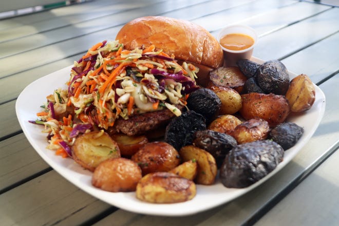 House of JuJu's "Dragon Lady" gourmet burger is served with their homemade spicy garlic aioli and house-pickled onions, topped with their signature teriyaki slaw. The dish comes with a side, this one happens to be their JuJu roasted potatoes.