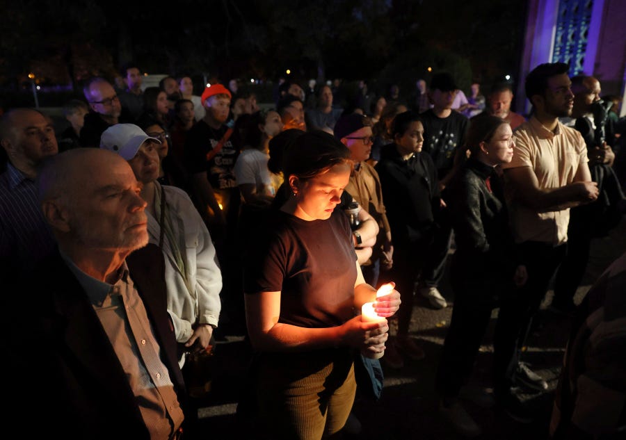 Marie Crane, center, holds a candle during a vigil in Tower Grove Park for the victims of a school shooting at Central Visual & Performing Arts High School in St. Louis on Monday, Oct. 24, 2022.