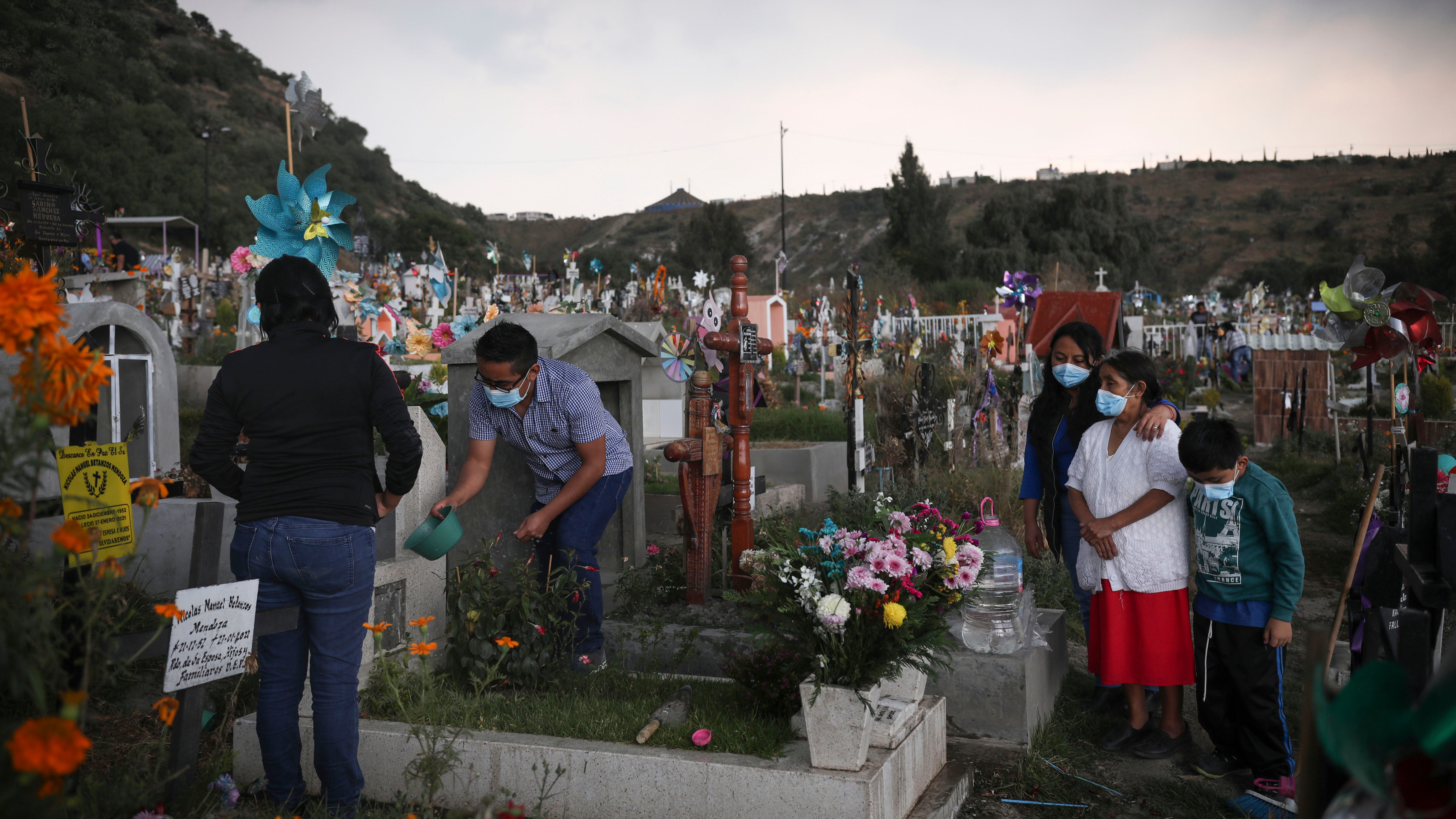 Family members tend to the grave of a relative in preparations for the Day of the Dead celebrations, at the Valle de Chalco municipal cemetery on the outskirts of Mexico City, Thursday, Oct. 28, 2021.