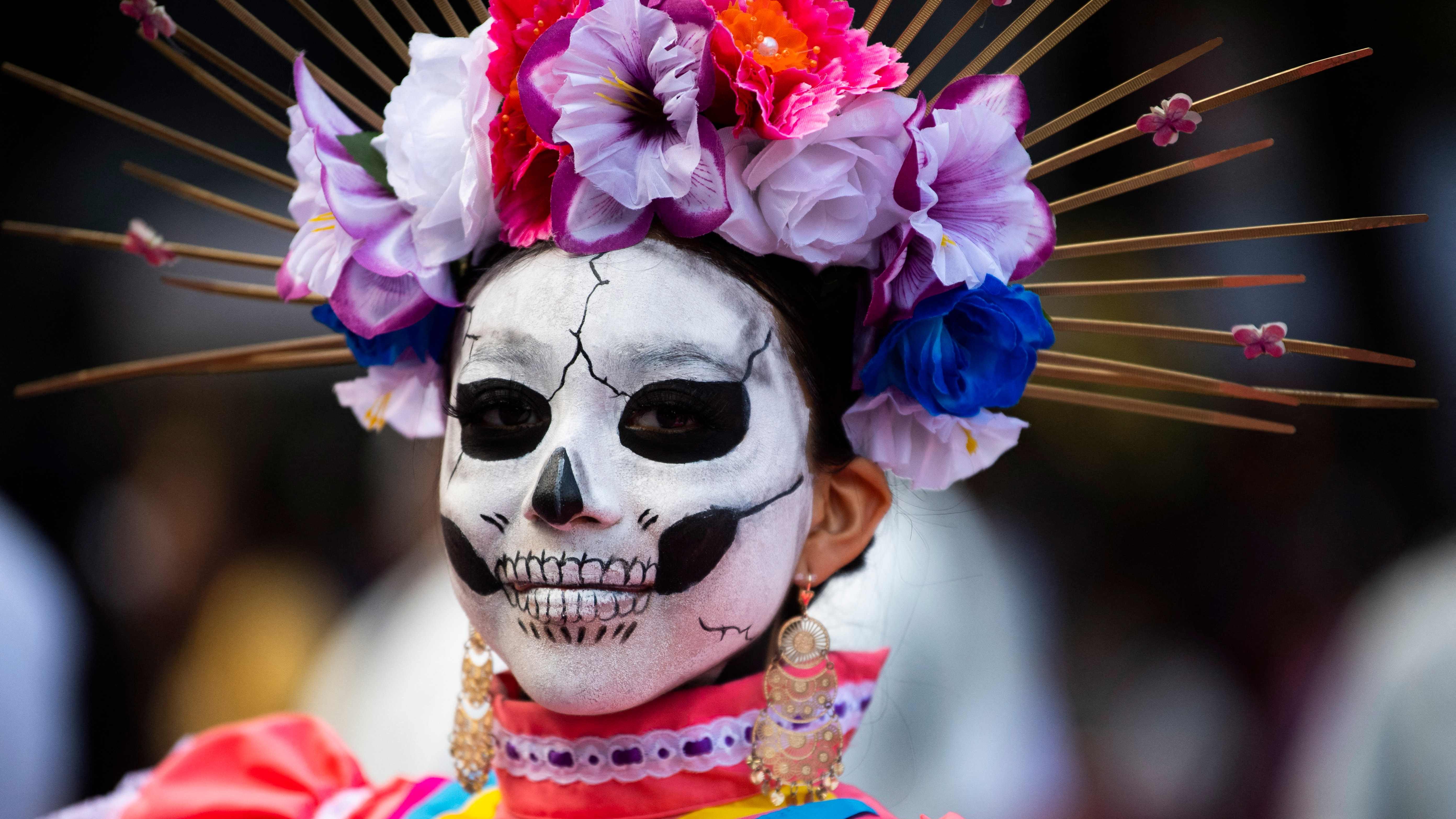 A woman fancy dressed as the character of La Catrina poses before taking part in the Catrinas Parade, commemorating the Day of the Dead, in Mexico City, on October 23, 2022.