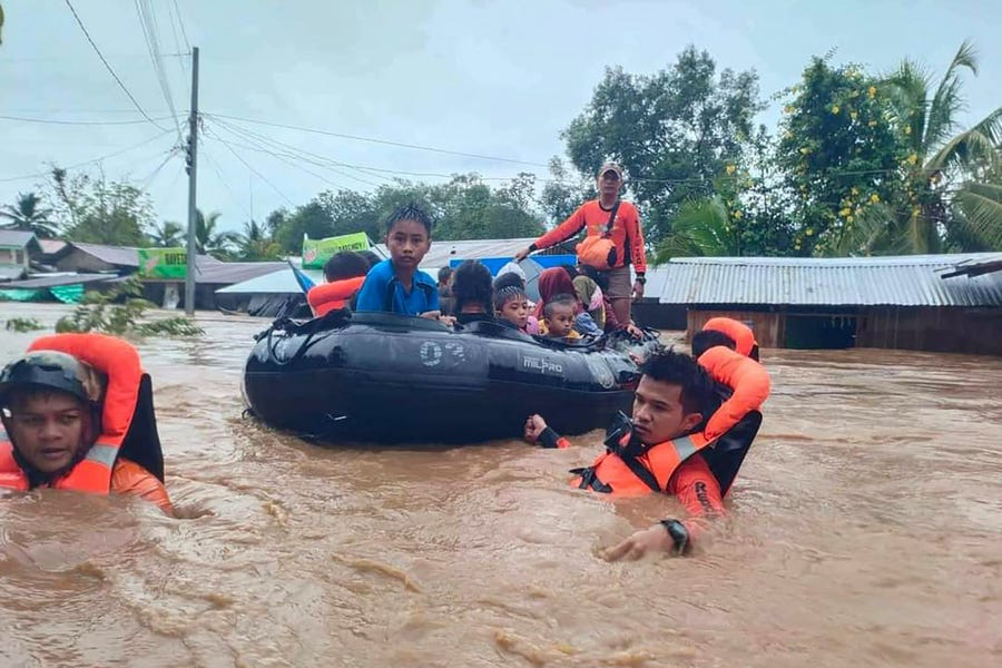 October 28, 2022: This handout photo taken and released by the Philippine Coast Guard shows rescue workers evacuating people from a flooded area due to heavy rain brought by Tropical Storm Nalgae in Parang, Maguindanao province. - Landslides and flooding killed 13 people as heavy rain from approaching tropical storm Nalgae lashed the southern Philippines on October 28, a disaster official said.