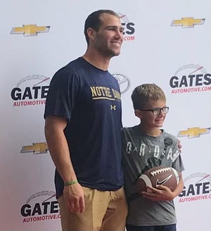 (l-r) Notre Dame linebacker Jack Kiser poses with Tyler Wimmer, 9, of Elkhart, during a promotional appearance on Aug. 20, 2022 at Gates Toyota in South Bend, Ind. After finding out Kiser wears No. 24, Tyler told his mother Samantha he would like to change his jersey number to '24' as well.