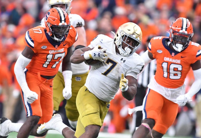Oct 29, 2022; Syracuse, New York, USA; Notre Dame Fighting Irish running back Audric Estime (7) runs between Syracuse Orange defensive lineman Steve Linton (17) and linebacker Leon Lowery (16) in the fourth quarter at JMA Wireless Dome. Mandatory Credit: Mark Konezny-USA TODAY Sports