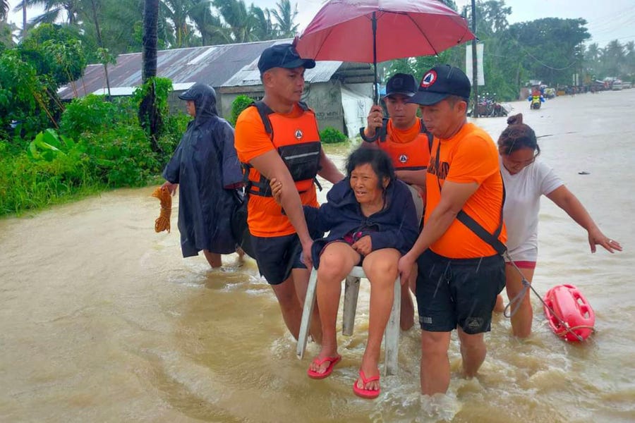 In this photo provided by the Philippine Coast Guard, rescuers evacuate residents from flood waters caused by Tropical Storm Nalgae in Hilongos, Leyte province, Philippines on Friday Oct. 28, 2022. Flash floods and landslides set off by torrential rains left dozens of people dead, including in a hard-hit southern Philippine province, where many villagers are feared missing and buried in a deluge of rainwater, mud, rocks and trees, officials said Saturday.