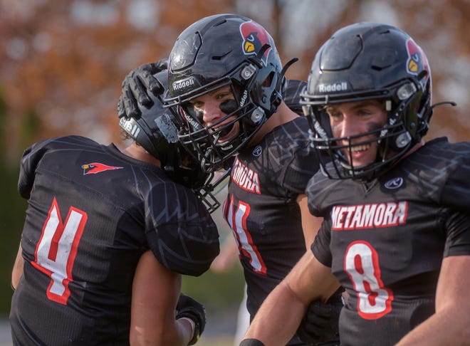 Metamora's Kameron Davis, left, Tyle Kasap, middle, and Jaden Hartnett celebrate a touchdown against Jacksonville  late in the second half of their Class 5A first-round playoff game Saturday, Oct. 29, 2022 in Metamora. The Redbirds advanced with a 68-34 victory.