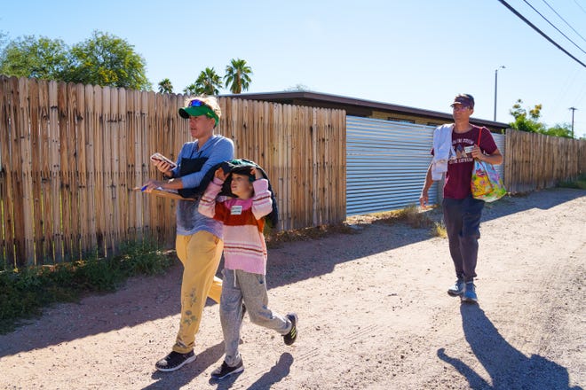 Carissa Sipp (left), Dan Hunt (right) and their daughter, Everest Sipp (middle) walk between houses while canvassing for the Environmental Voter Project on Oct. 29, 2022, in Tucson. They travel to the homes of people who have been identified as likely to take the environment into consideration when making voting decisions.