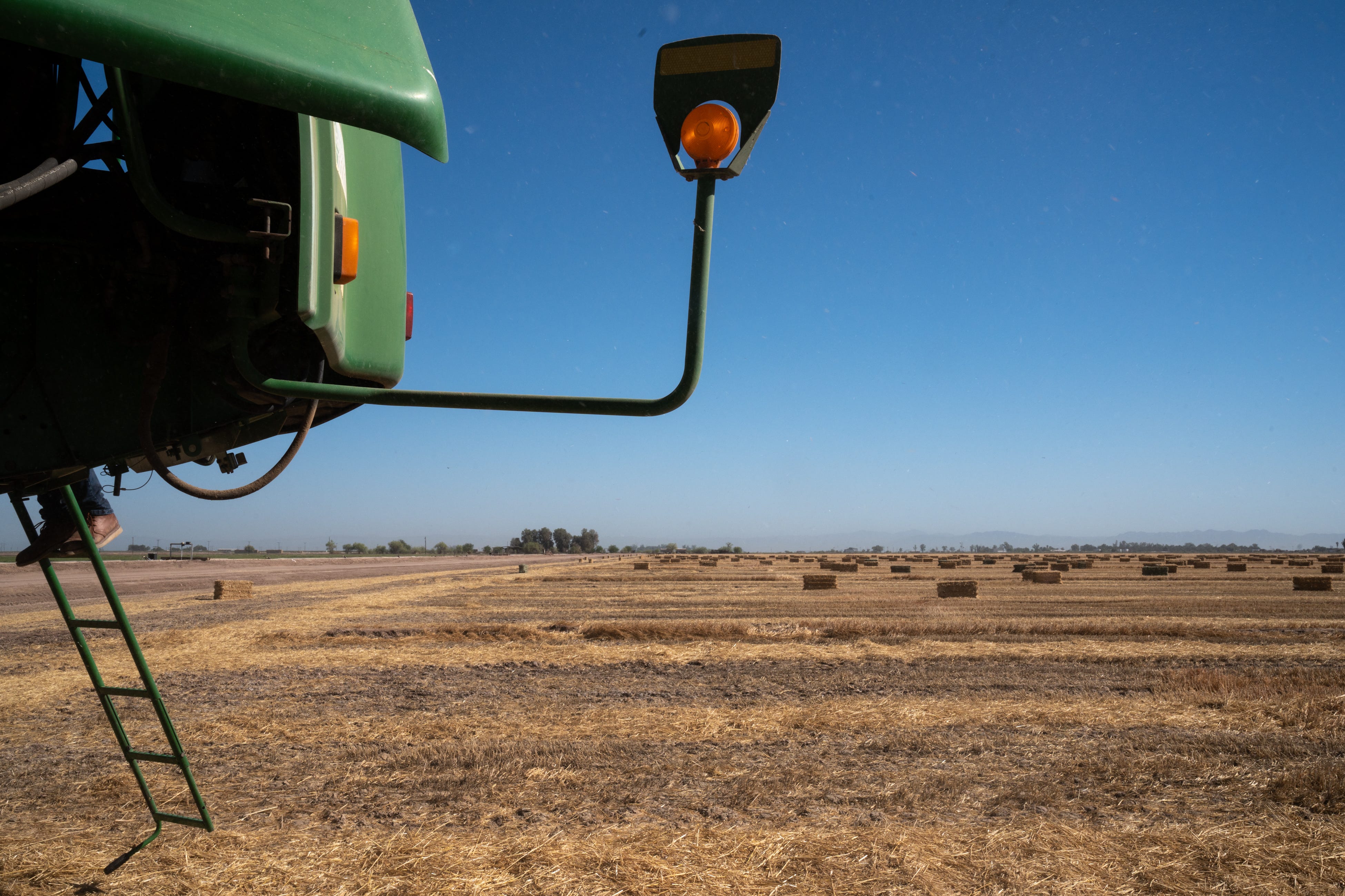 Albert Romero works on his combine before harvesting wheat on June 1, 2022, north of El Centro, California.