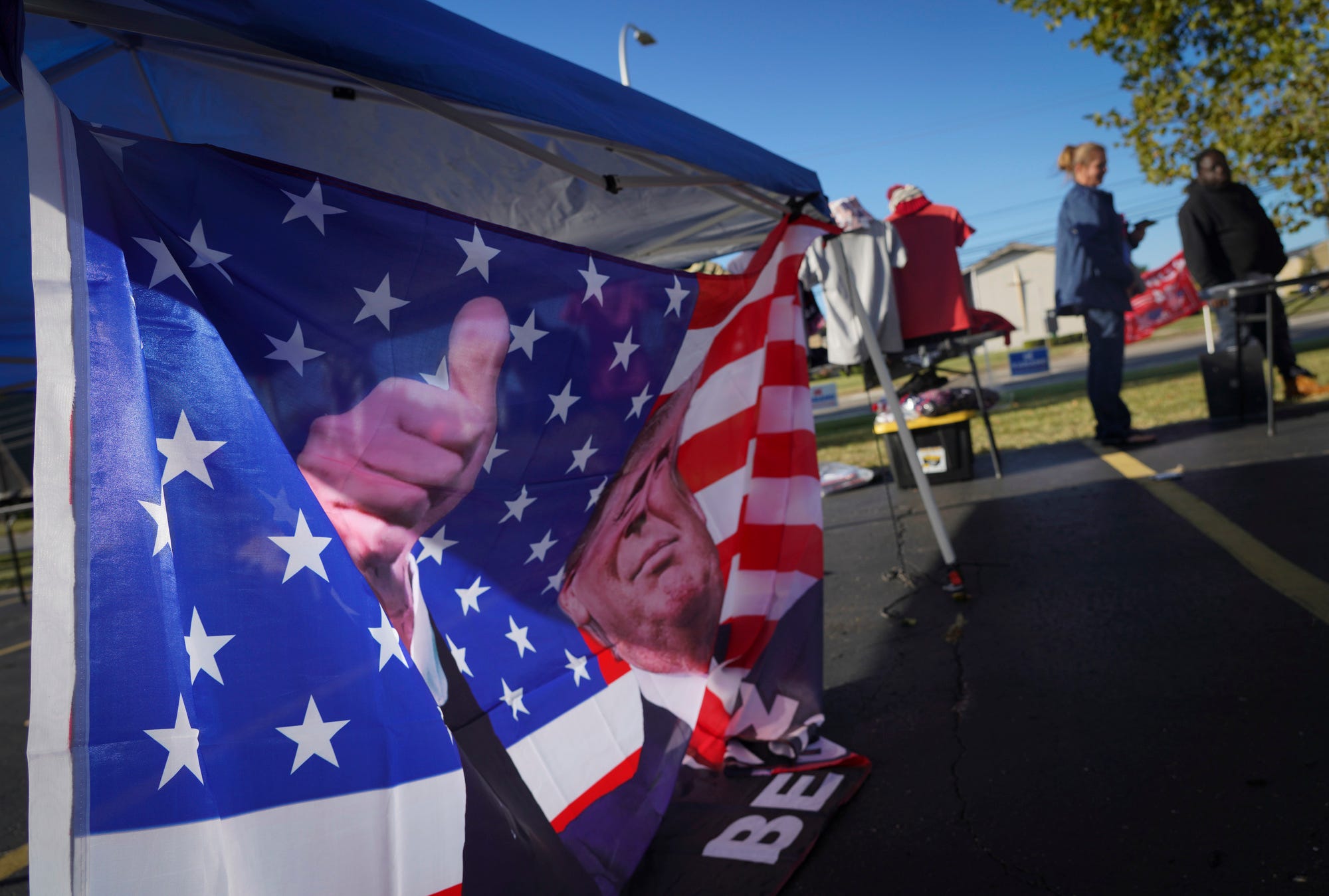 A person attending a Donald Trump rally held Oct. 1, 2022, at Macomb Community College in Warren, Michigan, talks to a vendor from North Carolina about buying a T-shirt.