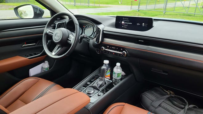 The 2023 Mazda CX-50's driver-oriented interior with hgh infotainment screen, remote controller, and sporty gauges.