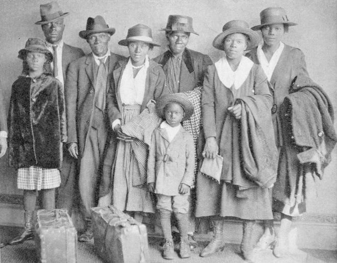 Photograph of African American men, women, and children who participated in the Great Migration to the north, with suitcases and luggage placed in front, Chicago, 1918.