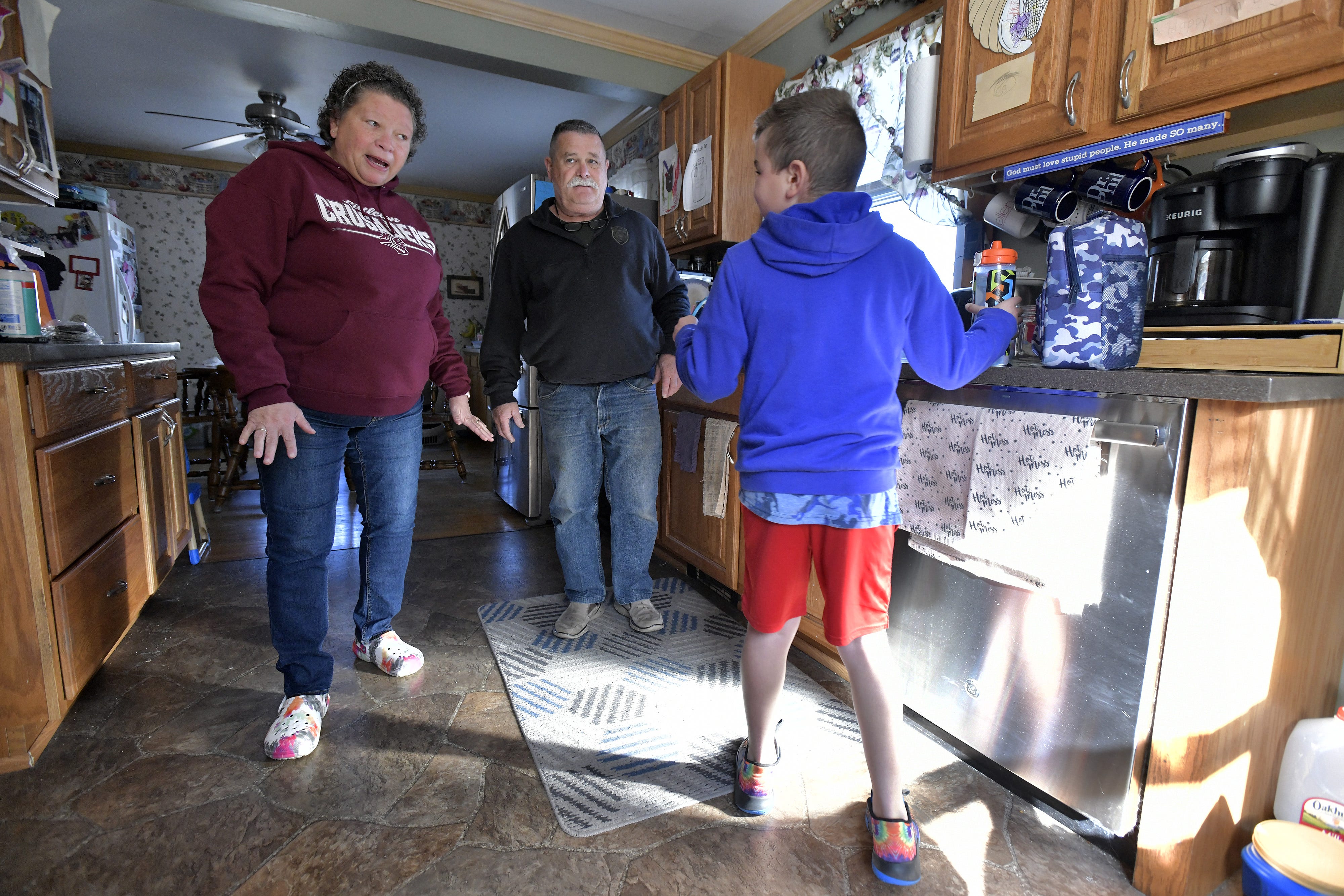 David Miller of Littleton, N.H., 61, looks on as his wife Tina Miller, left, and Kah'leal Oliver, 8, center, one of three children that the Millers are caring for, prepare to go to a Sunday afternoon soccer game and David goes to work.