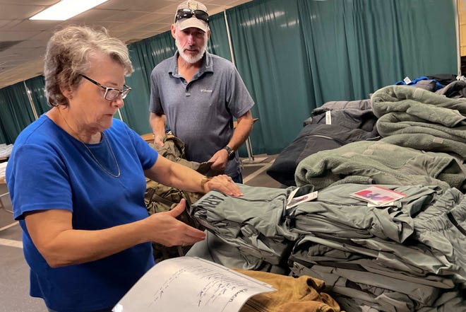 Volunteers Rita Smith and Rick Mobley fill a backpack with cold-weather clothing for a veteran during the Okaloosa County Veteran Standdown on Wednesday at the Northwest Florida Fairgrounds in Fort Walton Beach.