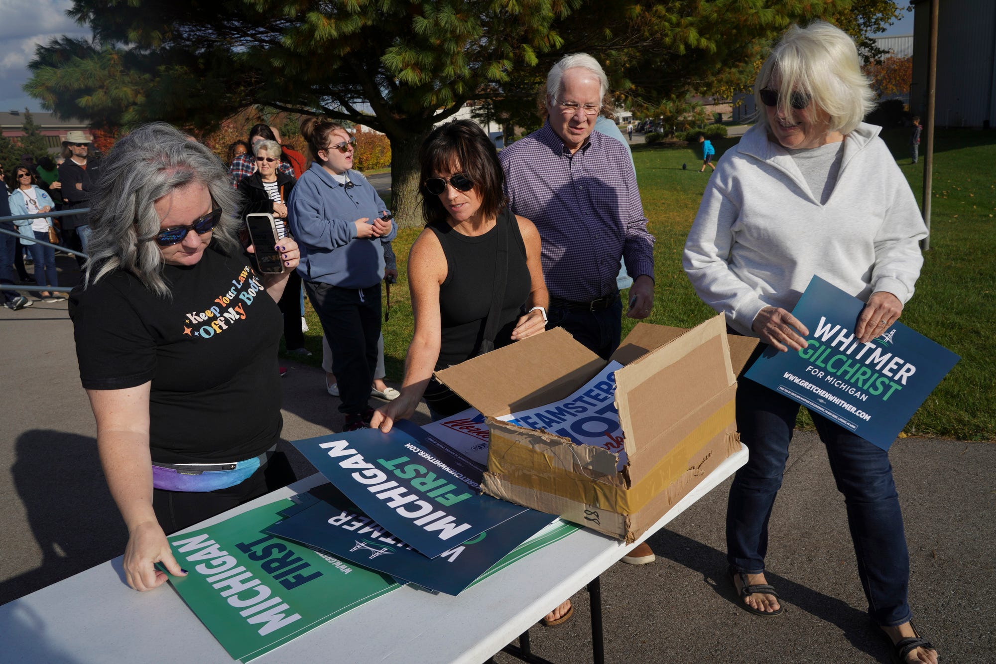 Supporters of Michigan Gov. Gretchen Whitmer grab campaign signs as they walk into a “Grillin’ with Gretchen” rally held in the parking lot behind the Teamsters Local 406 building in Wyoming on Oct. 23, 2022.
