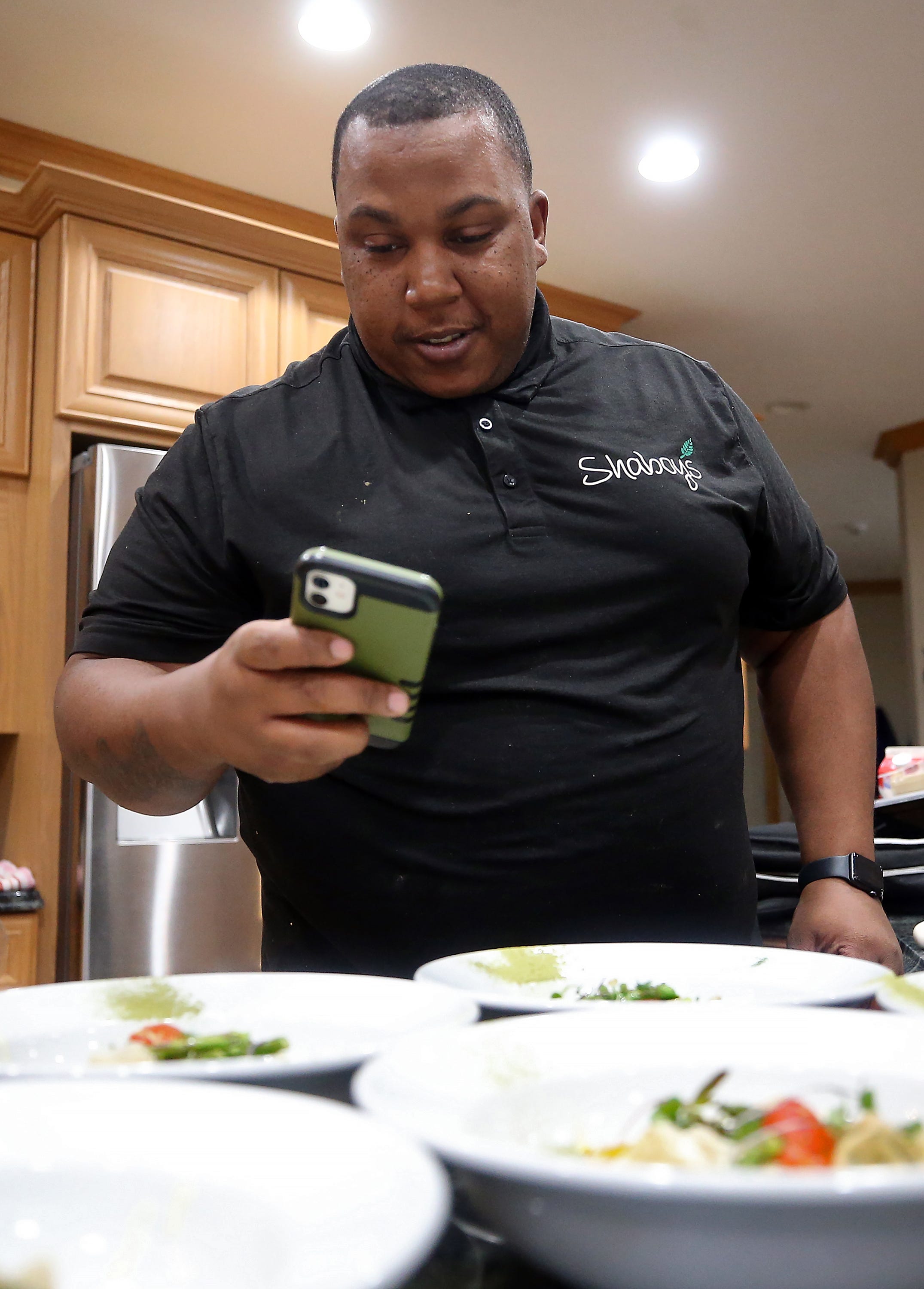 Private chef Dion Millender snaps a few photos of his dishes for his Instagram page @shaboys_akron before serving at a client's home, Sunday, Oct. 30, 2022, in Akron, Ohio.