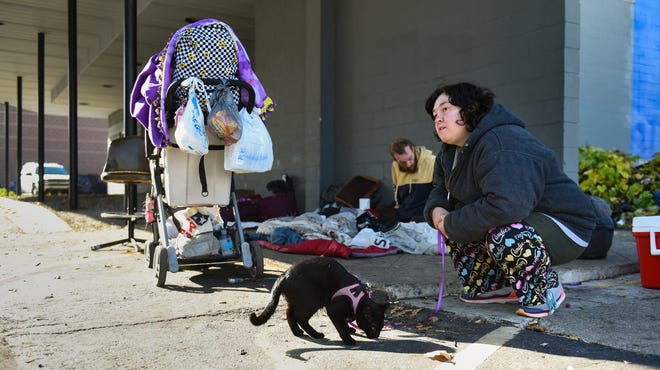 "We're just gonna try to find a motel room for tonight, I'm not sure where else to go since it's difficult to find any shelters or housing that allow cats," newly displaced Lansing resident Desiree Kaiser, 29, said. Seen here Tuesday, Nov. 1, 2022, near the downtown CATA bus station. Seven-weeks pregnant, she says "I have anxiety and this cat is my service animal." She says it's their first day living without permanent housing. Pictured in the background is her long time friend Darcy Wildman, 36, who has been living under a parking structure.