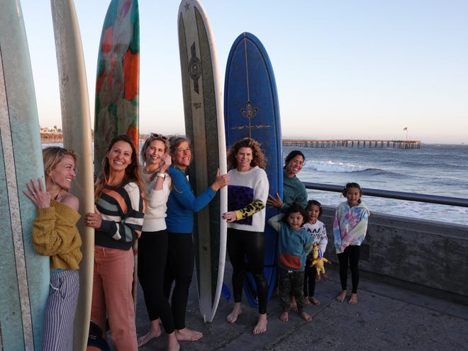 A local surf group, Mondos Mary Surf Sisters, is hosting its first-ever paddle-out in Ventura on Sunday to honor Mary Monks, who rode local swells while wearing wool sweaters in the 1950s. From left, Erin Chadwick, Amber Inggs, Dana Bisenius, Kim "Flow" Hansmeier, Keri Nesbitt and Tammy Takara, with children Holden, Gwen and Summer, pose on the Ventura Promenade on Wednesday.