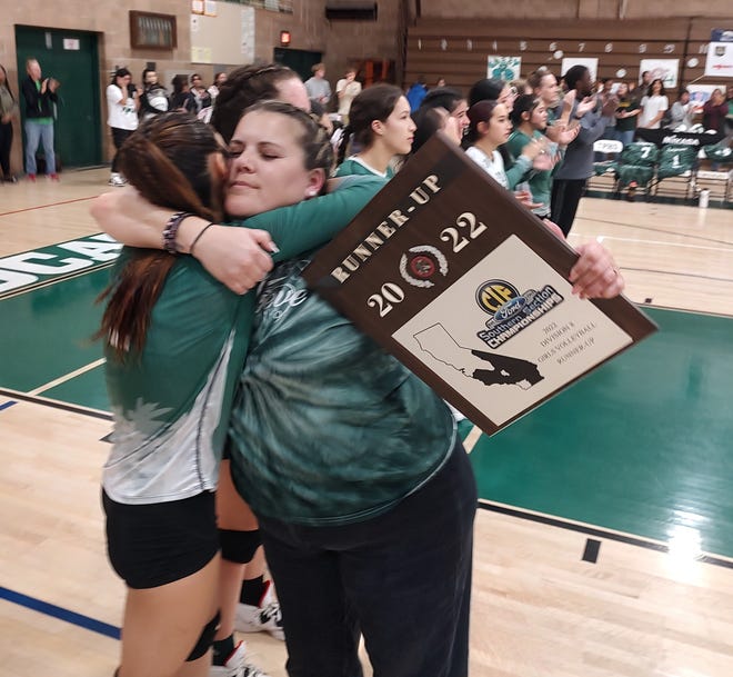Twentynine Palms coach Melissa McGivern hugs her players while holding the CIF-SS Division 8 runner-up plaque after the Wildcats lost to United Christian Academy on Saturday.