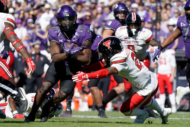 TCU running back Kendre Miller (33) carries the ball past  Texas Tech defensive back Dadrion Taylor-Demerson (25) during the second half at Amon G. Carter Stadium.