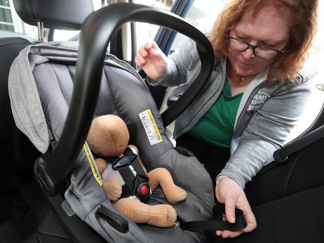 Хедър Трънка, ръководител на превенцията на наранявания в Детската болница в Акрон и щатски директор на Safe Kids в Охайо, затяга колана за бебета, след като монтира столче за кола, обърнато назад.