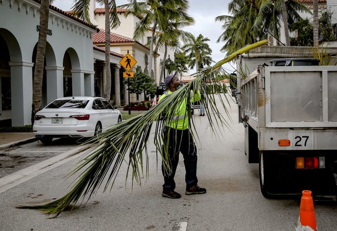 A Palm Beach Public Works employee removes tree debris from Worth Avenue on Sept. 29, the day after Hurricane Ian made landfall on the state's Gulf Coast.
