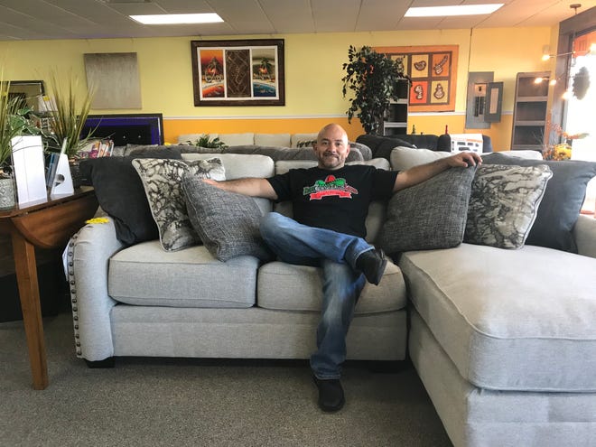 HomeTown Furnishings owner Omar Cruz relaxes on a couch that is available for purchase in his newly reopened store on Broadway in Taunton.