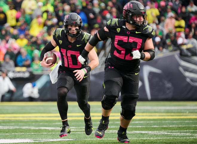 Oregon quarterback Bo Nix (10) carries the ball with help from offensive lineman Ryan Walk (53) during the team's game against UCLA at Autzen Stadium.