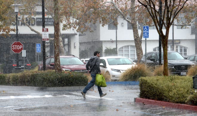 A shopper runs in in a downpour outside Gelson's market in the Westlake Plaza and Center during a November storm.