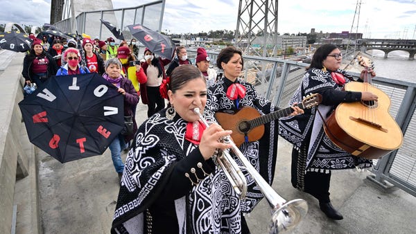 A Mariachi band leads a group of Latino and immigr
