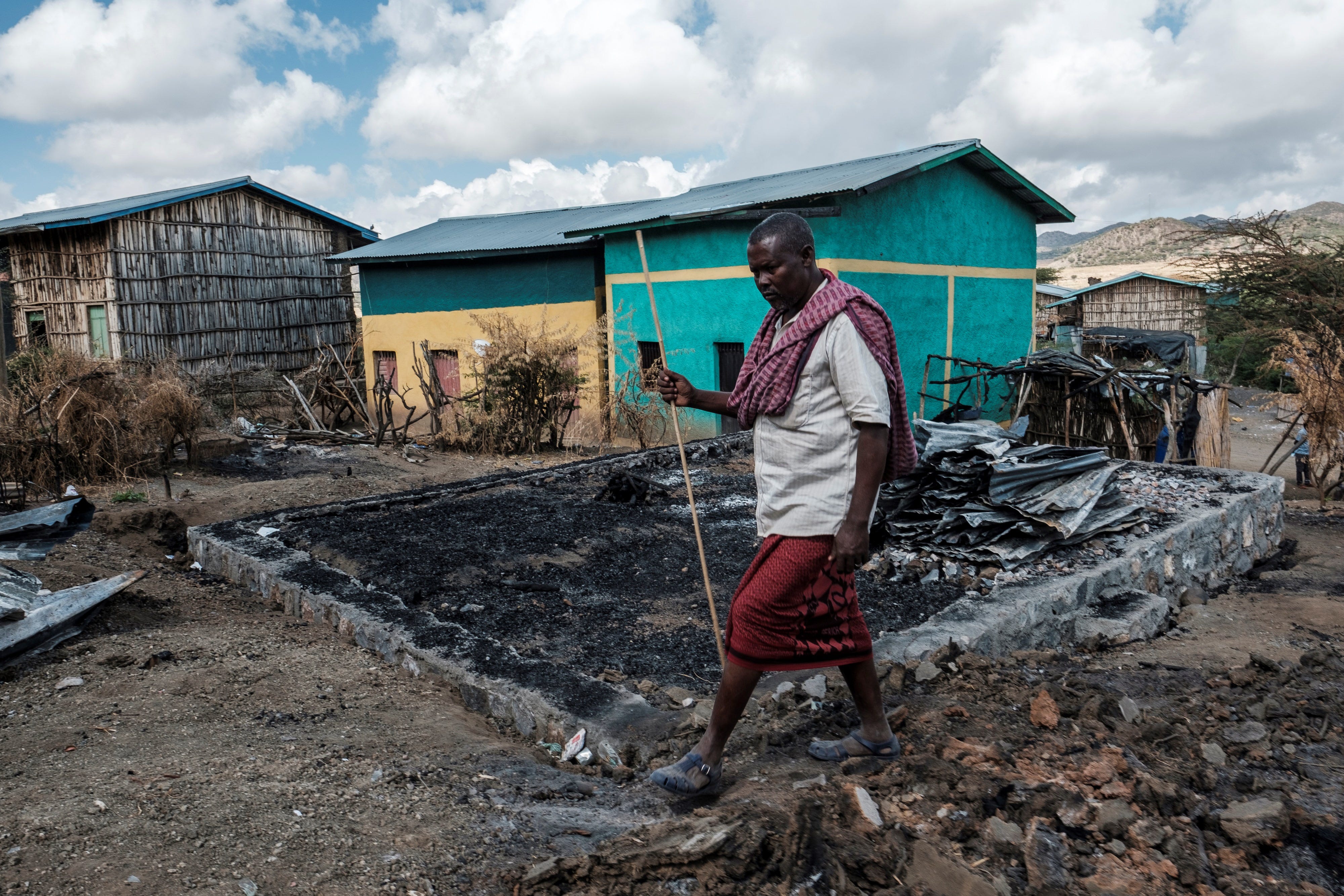 Addis Sissay, 49, walks in front of his destroyed house in the village of Bisober in Ethiopia's Tigray region in December 2020.