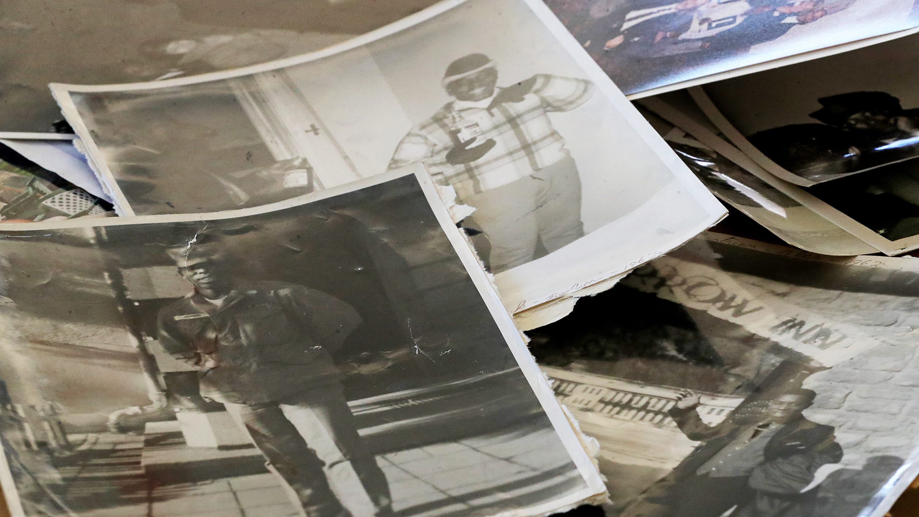 Photographs of U.S. Army veteran Moses Herrin's travels are scattered on a table.