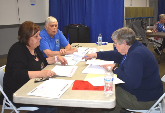 Nancy O'Connor, left, Mike Root, second from left, and Diane Bach, right, work on sorting through envelopes and ballot documents  after the voting polls closed at 8 p.m. Tuesday night in Adrian at the Lenawee County Fair & Events Grounds in the Merchants Building.